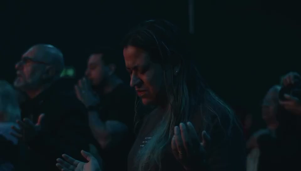 Pessoas adorando de olhos fechados durante o culto
